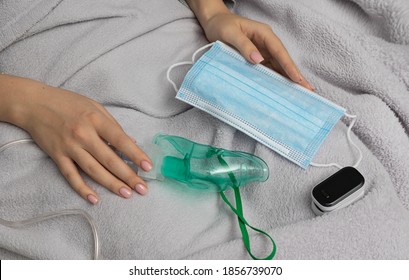 Self-diagnosis Of Oxygen Deficiency. Pulse Oximeter, Protective Mask And Inhaler In Woman Hands. Health Concept And Virus Protection Concept