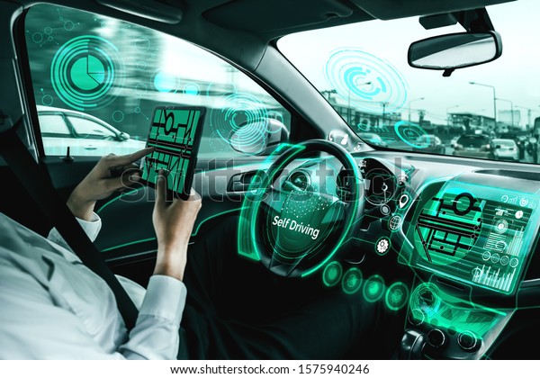 Self-driving autonomous car with relaxed young\
man sitting at driver seat is driving on busy highway road in the\
city. Concept of machine learning, artificial intelligence and\
augmented reality.