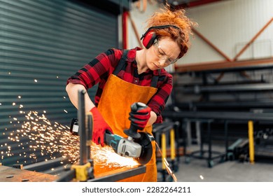 A self-employed worker is cutting a metal beam using a grinder, she is focused on her work and wearing protective gear - Powered by Shutterstock