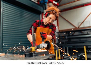 A self-employed worker is cutting a metal beam using a grinder, she is focused on her work and wearing protective gear - Powered by Shutterstock