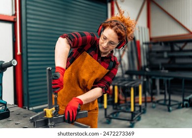 A self-employed worker using a clamp for metal beam , she is focused on her work and wearing protective gear - Powered by Shutterstock