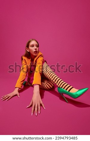 Self-expression. Modern fashion. Portrait of young girl, lady in unusual, strange colorful outfit and posing against magenta color studio background. Concept of surrealism, art, queer, beauty, ad.
