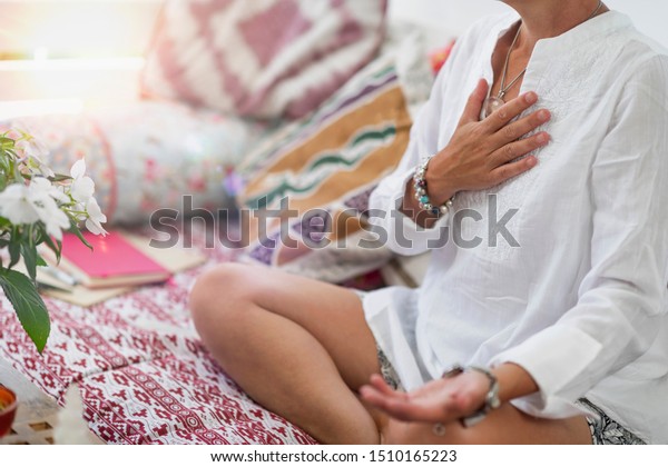 Self-Healing Heart\
Chakra Meditation. Woman sitting in a lotus position with right\
hand on heart chakra and left palm open in a receiving gesture.\
Self-Care Practice at\
Home