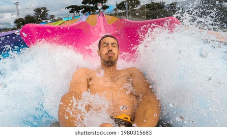 Selfie 40s Man Sliding A Water Slide Very Fast, Splashing Into The Pool With Water Drops On The Face. Having Fun At A Water Amusement Park On Summer Vacation.