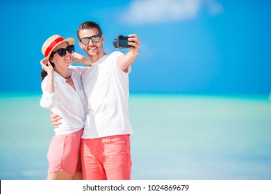 Selfie couple taking pictures on the beach. Tourists people taking travel photos on their holidays. - Powered by Shutterstock