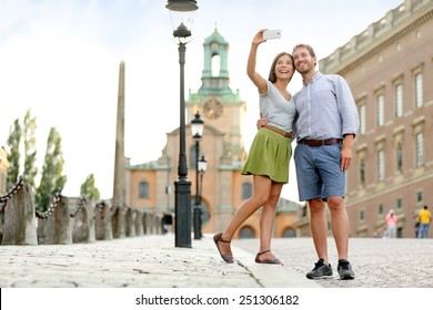 Selfie Couple Taking Pictures At Stockholm Cathedral And Royal Palace In Gamla Stan (Old Town) In The Capital Of Sweden. Tourists People Taking Travel Photos With Smartphone On Summer Holidays.