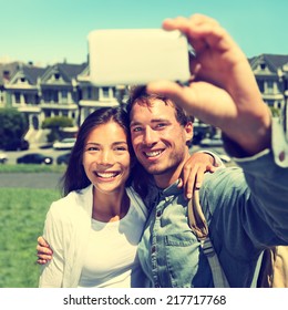 Selfie - Couple Taking Self-portrait Photo In San Francisco With Smartphone Camera. Happy Tourist Couple On Travel Vacation In San Francisco, Alamo Square, USA. Heavily Filtered Instagram Style.