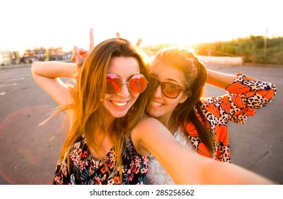 Selfie fun girls taking picture at cool sunset.Summer holidays, girls at smartphone camera taking self-portrait on their travel vacations.Best friends girls make picture at sunset,camera selfie pic - Powered by Shutterstock