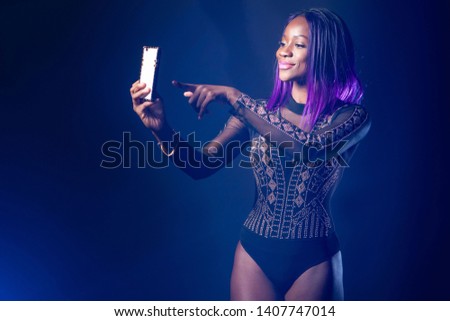 Selfie girl. Black model with purple hair makes a selfie photo. Selfshot. A self-portrait photo. Photo for social networks. Egomania. Posing. Fashion trend.