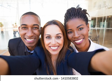 Selfie Of Happy Beautiful Intercultural Business Friends In Office. Smiling Pretty Woman Taking Group Photo With Black Colleagues. Staff Relationship Concept