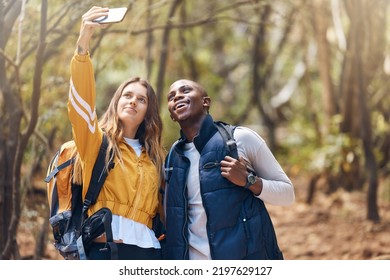 Selfie, Happy Couple And Hiking Adventure While Holding Phone For Vacation Travel Memories In A Forest Or Woods. Happy, Love And Exercise In Healthy Relationship With Black Man And White Woman