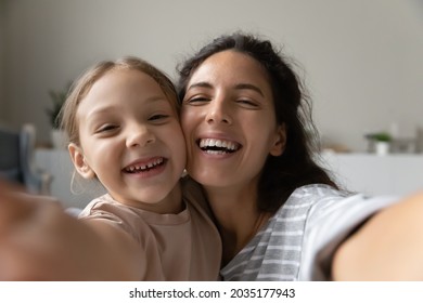 Selfie Of Happy Young Mom And Sweet Little Daughter Girl Looking At Webcam With Toothy Smile. Mother And Kid Taking Self Portrait Picture On Smartphone Holding Gadget With Web Camera In Hand