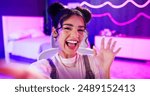 Selfie, influencer and girl with live streaming update in neon bedroom for social media audience, fans or followers. Face of excited content creator, gamer or streamer with wave hello in virtual post