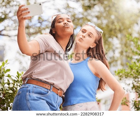 Selfie, kiss and women friends bonding, chilling or hanging out outdoor in the park. Love, friendship and happy interracial females taking cute picture with a pout together in nature in green garden.