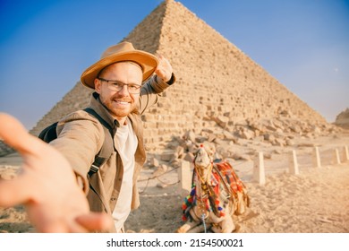 Selfie photo man in hat background pyramid of Egyptian Giza and camel, sunset Cairo, Egypt.