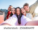 Selfie portrait of a group of young multiracial teenagers having fun on a friendly meeting. Five mixed friends smiling and laughing. Students looking at camera together. Men and women enjoying. High