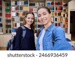 Selfie portrait of two girls high school students looking at camera inside classroom