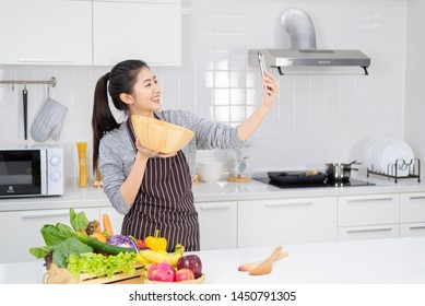 Selfie with a salad in a modern kitchen,Beautiful woman taking selfies while cooking in the modern kitchen. Healthy food and fasting concepts - Shutterstock ID 1450791305