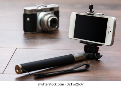 Selfie stick and smart phone and blurred retro camera - Powered by Shutterstock