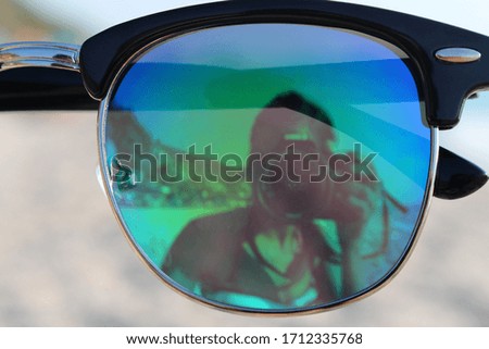 Selfie in a sunglasses lens on the beach.