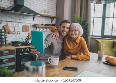 Selfie together. Young handsome man in grey shirt and his mom making selfie - Powered by Shutterstock