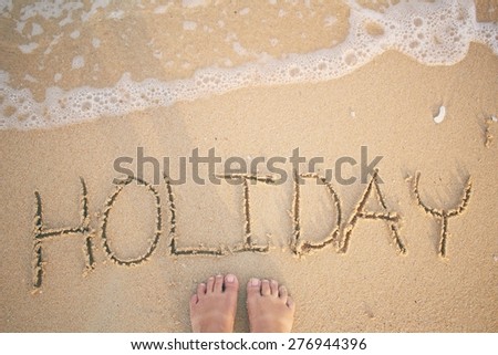 Selfie of word holiday written in sand on beach 