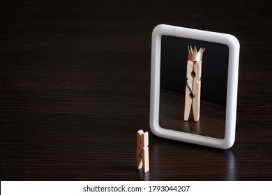 selfish concept. small clothespin seeing himself in the mirror as big king with crown