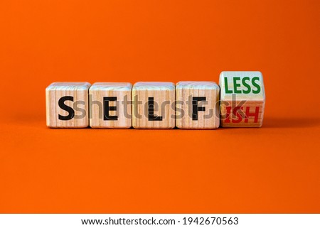 Selfish or selfless symbol. Turned cubes and changed the word 'selfish' to 'selfless'. Beautiful orange background, copy space. Business, psuchological and selfish or selfless concept.