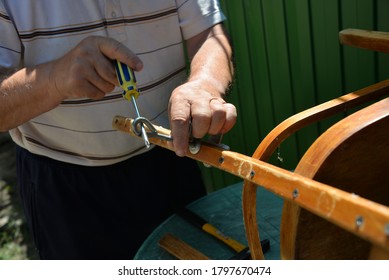 A Self-isolation Class Is A Chair Repair. Grandfather Repairs A Chair On The Street, Using Screws, Glue, And A Vice.