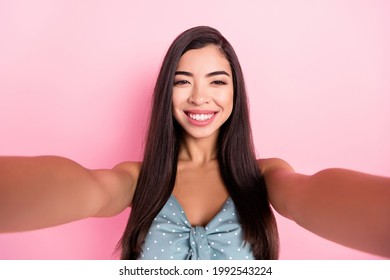 Self-portrait of attractive cheerful woman wearing pin-up summer top isolated over pink pastel color background