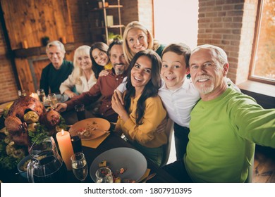Self-portrait of nice cheery big full family brother sister grandparents grandson granddaughter sitting around served festal table embracing reunion at modern loft industrial brick interior house
