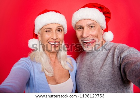 Self-portrait of two nice childish playful crazy cheerful positive glad grey-haired spouses husband wife grimacing winking blinking enjoying isolated over red pink background