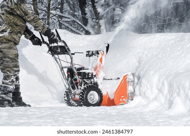 The self-propelled snow-plough blower. The man in warm clothes gloves instead of the big shovel has chosen a self-propelled engine snowplow outdoors white snow - Powered by Shutterstock