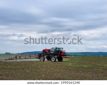 Self-propelled sprayer working in the field during spring in Romania. Applying pesticides on a young corn field.