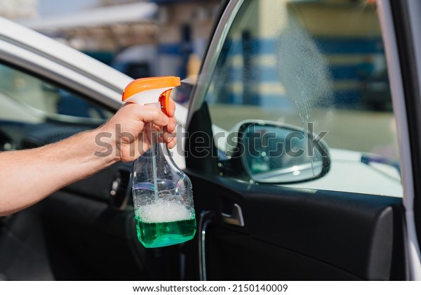self-service car wash. a man washes the car\
window with glass cleaning liquid. professional cleaning of\
transport. car\
washer.