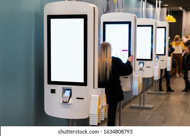 Self-service desk with touch screen and payment terminal in fast food restaurant