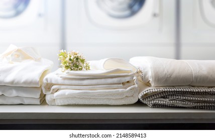 Self-service laundry for the public with bedding and staff on a white bench and professional washing machines in the background. Front view. Horizontal composition. - Shutterstock ID 2148589413