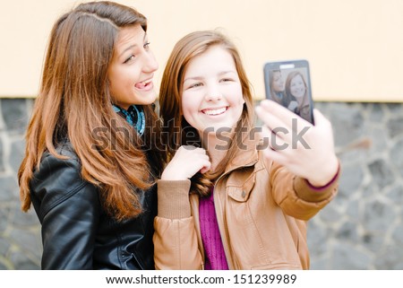 selfshot or selfy portrait: Two teen girls taking picture of themselves using tablet pc outdoors happy smiling and having fun 