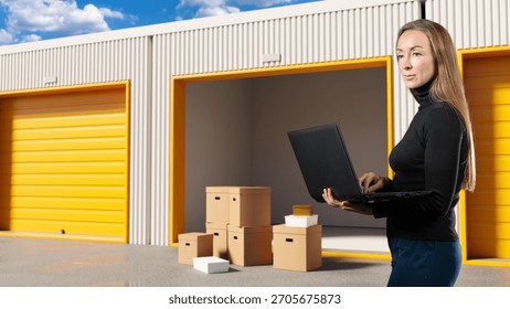 Self-storage manager checks inventory data on a laptop while overseeing packed boxes arranged outside open storage units, organizing goods and monitoring unit usage.