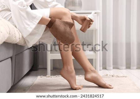 Self-tanning. Woman applying cosmetic product onto leg with tanning mitt on bed at home, closeup. Space for text
