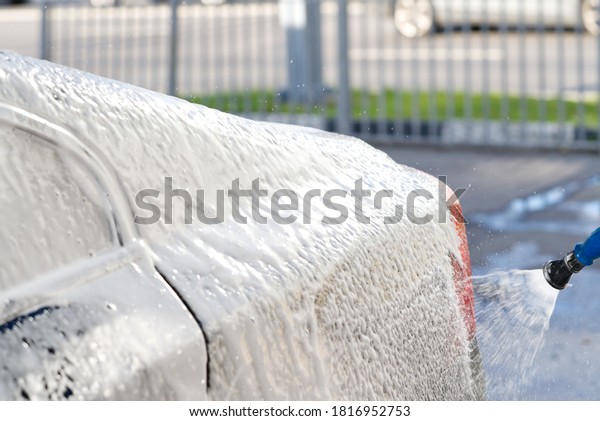 self-washing the car, covering the bumper\
with car shampoo, black car washing, selective\
focus