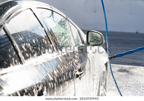 self-washing the car, covering the roof\
with car shampoo, black car washing, selective\
focus