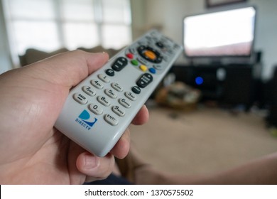 Selinsgrove, PA - April 15, 2019 - Close-up Of A Directv Remote In Hand Pointed At A TV. Selective Focus And Shallow Depth Of Field - Image