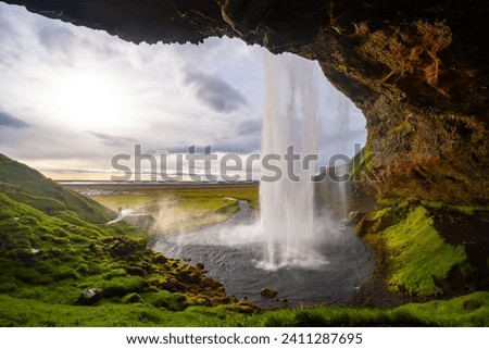 Seljalandsfoss is an impressive cascade on the south coast of Iceland. Majestic waterfall seen from a cave behind. Colorful scenery and major tourist attraction and sight in wild volcanic nature.
