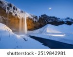 Seljalandsfoss waterfall, Iceland. Icelandic winter landscape. High waterfall and rocks. Snow and ice. Powerful stream of water from the cliff. A popular place to travel in Iceland.