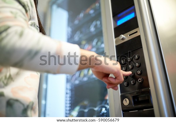 sell, technology and\
consumption concept - hand pushing button on vending machine\
operation panel keyboard