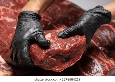 Seller in black uniform in shop market holds big piece of fresh raw calf beef bull sirloin ribeye steak . seller shows costumer meat. closeup front view. banners advertising advertisment banner mockup - Powered by Shutterstock