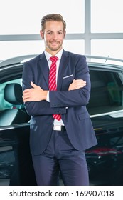 Seller Or Car Salesman In Car Dealership Presenting His New And Used Cars In The Showroom