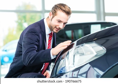 Seller Or Car Salesman In Car Dealership Presenting The Reflecting Car Paint Of His New And Used Cars In The Showroom