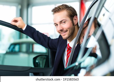 Seller Or Car Salesman In Car Dealership Presenting His New And Used Cars In The Showroom